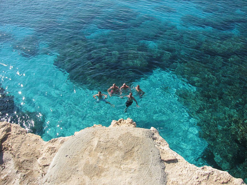 A small group of male swimmers enjoy the crystal clear waters around the infamous sea caves in Cyprus&#039; Cape Greco National Park