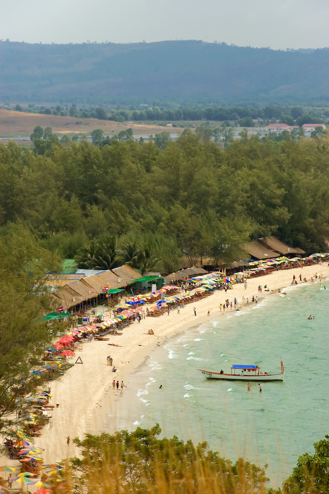 Panoramic view of the Cambodia&#039;s Sihanoukville Beach filled with activity including boats, beach goers, and adventure enthusiasts