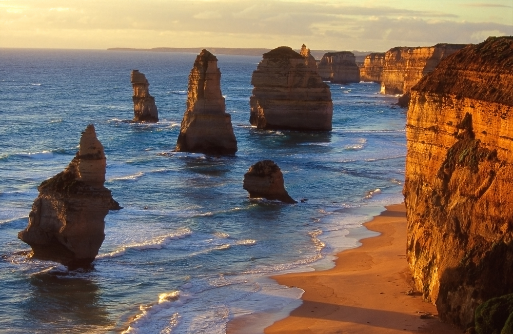 Formed by erosion, the Twelve Apostles lie off the shore of Port Campbell National Park near the Great Ocean Road in Victoria, Australia; these limestone stacks are a popular attraction among tourists.