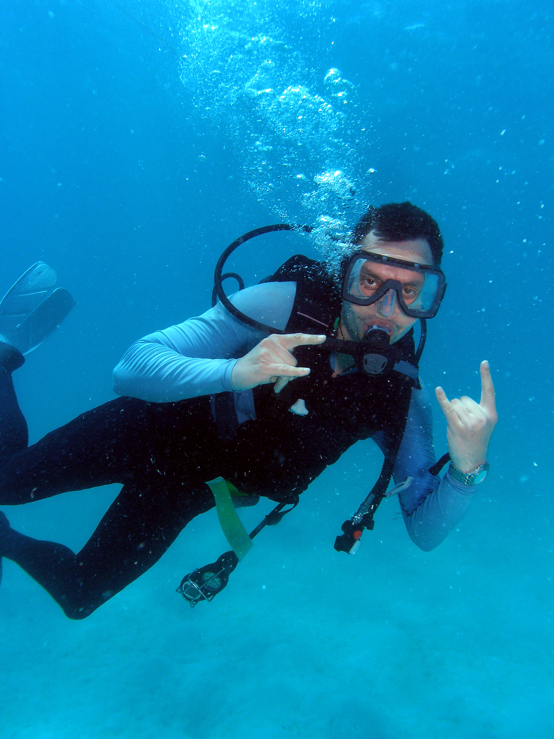 Male diver use the hang loose scuba hand signal to tell his dive buddy to relax and enjoy the surroundings