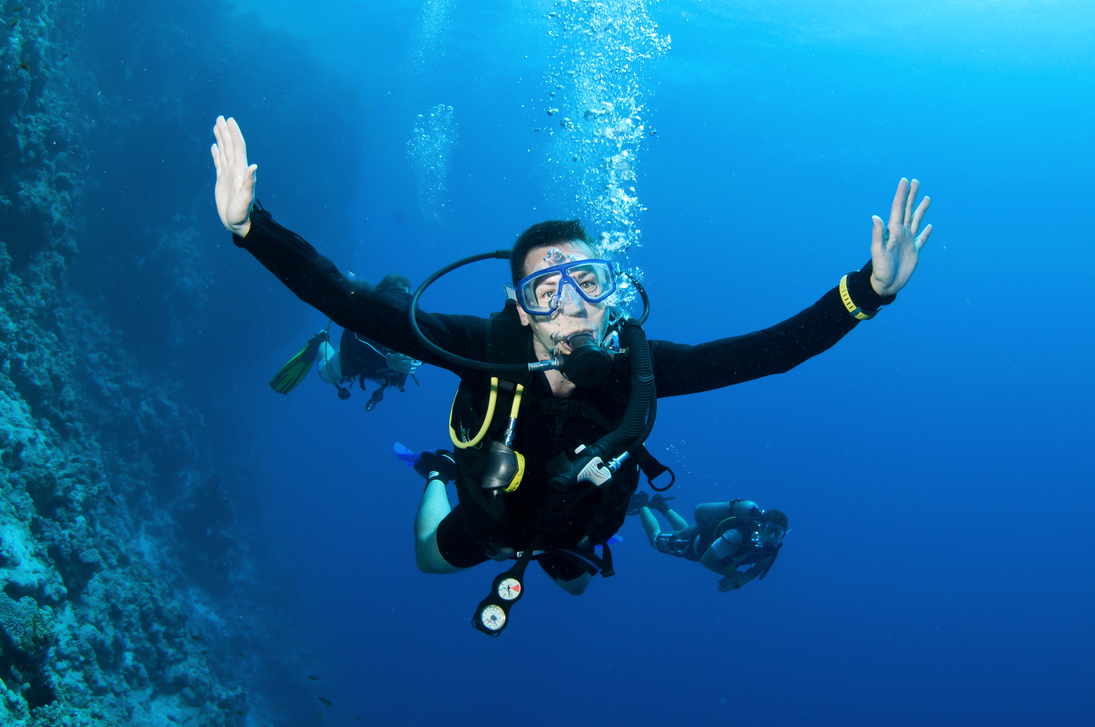 Male diver uses the manta ray hand signal to tell other divers in his group that a manta ray is near