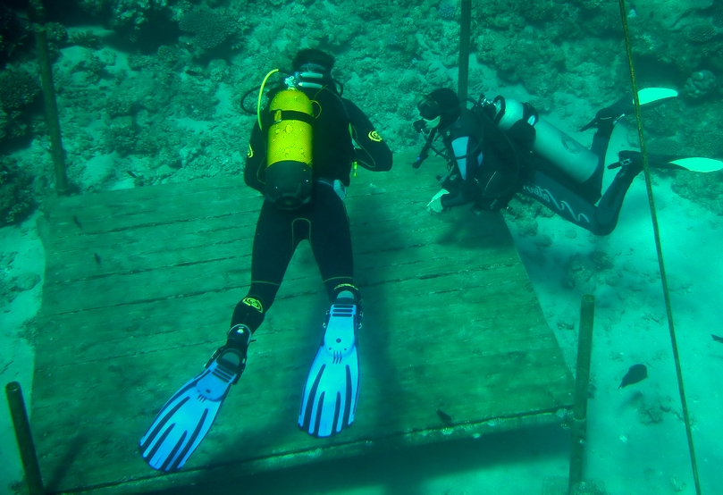 Diver swimming towards his buddy in an attempt to practice buddy breathing, an important skill to prevent scuba diving accidents