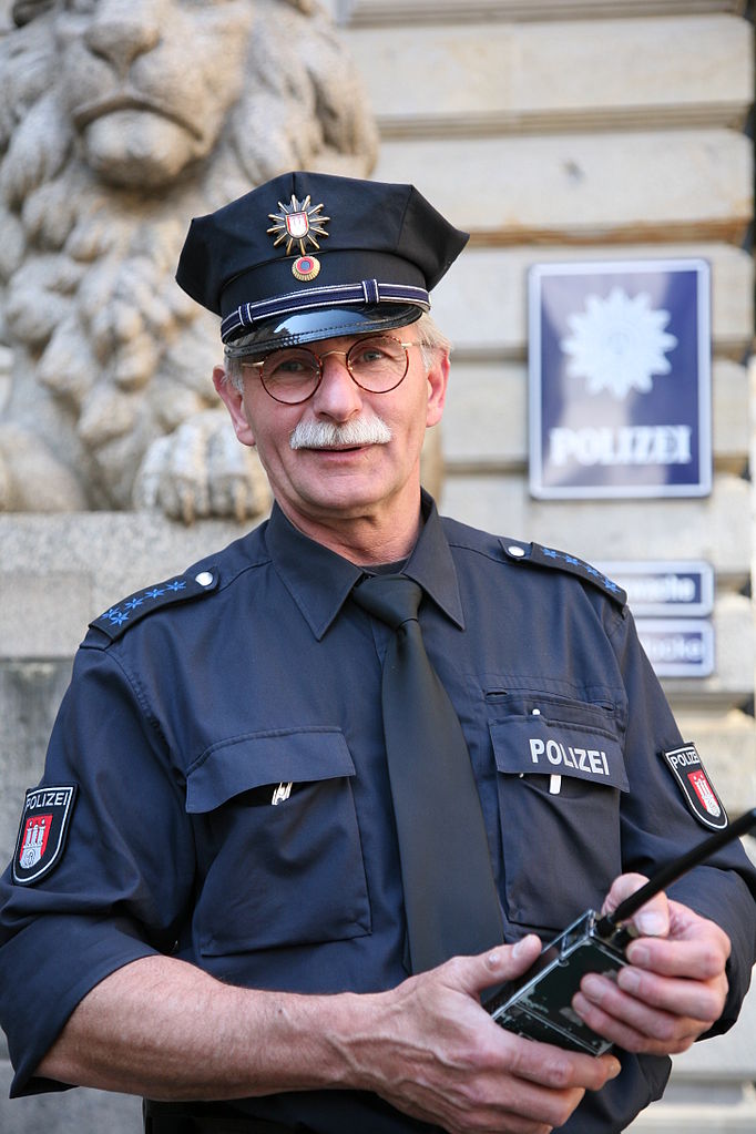 Police officer in Hamburg, Germany with a walkie talkie; being familiar with local law enforcement uniforms and cars will help avoid fake police scams