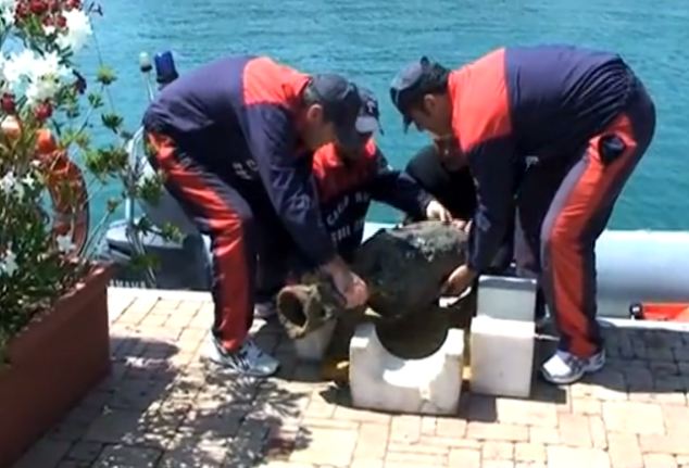 Police divers in Varazze, Italy place a pot recovered from a 2,000 year old wreck on shore for further examination