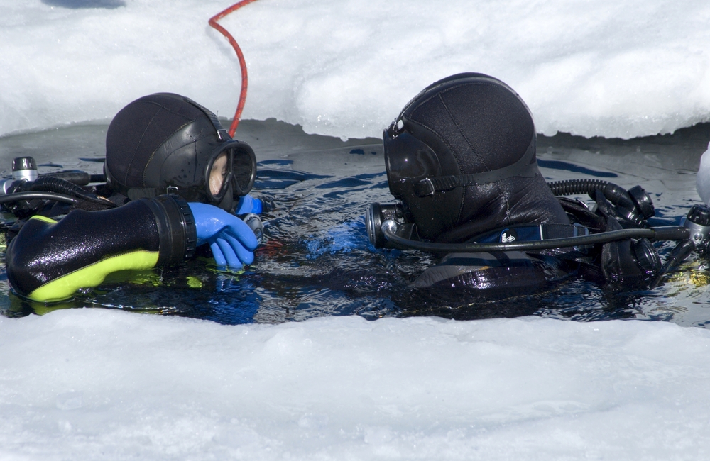 Two dive buddies enter hole in ice in Russia's White Sea and prepare for their descent