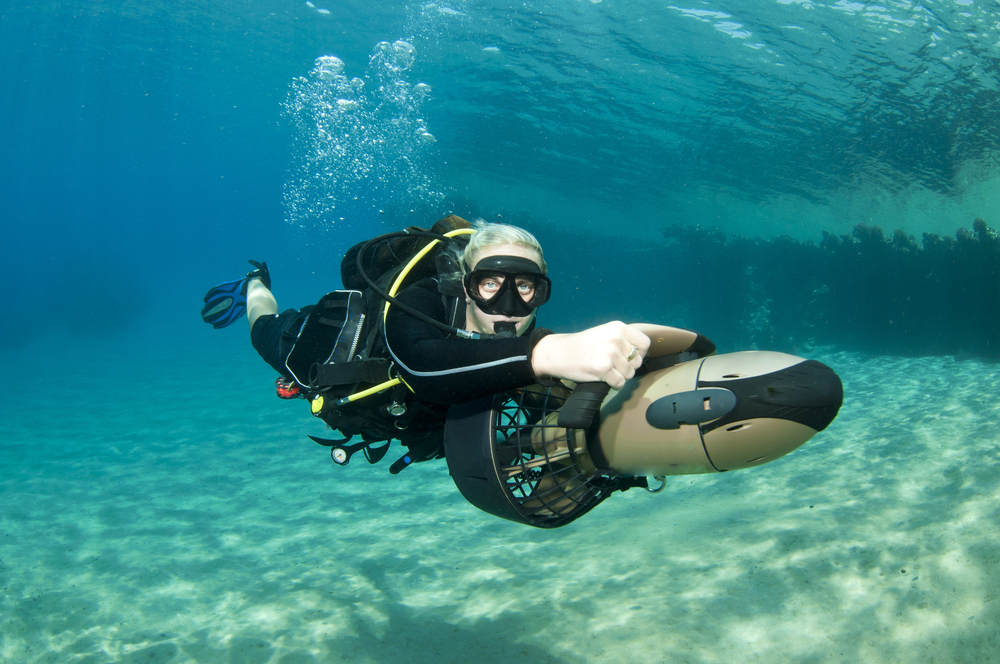 Female scuba diver enjoying a ride on a diver propulsion vehicle (dpv) in the warm, tropical waters of the Caribbean