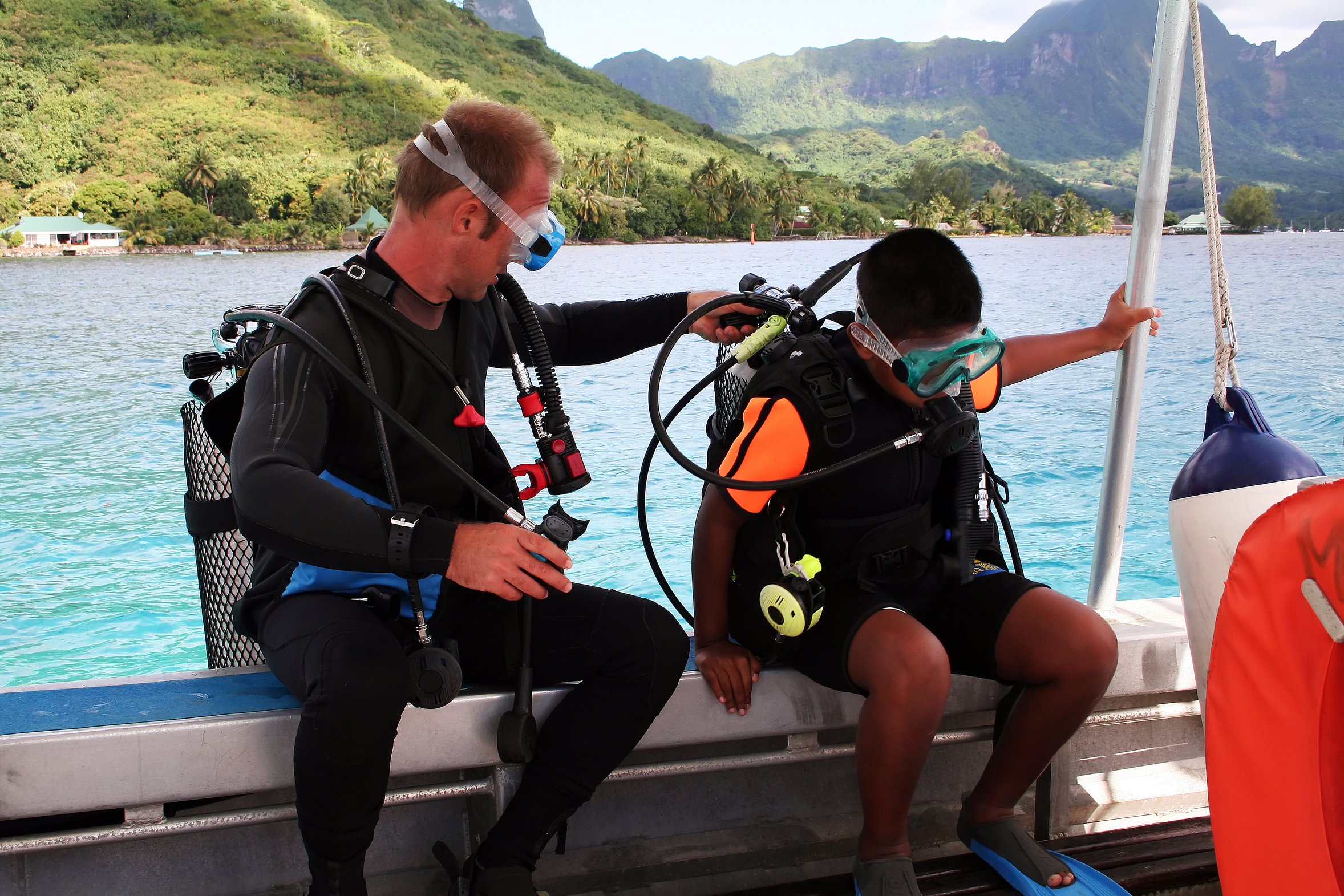 Two scuba divers become dive buddies and perform their pre-dive buddy check on the dive boat before taking a giant stride into the big blue ocean