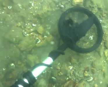 Underwater treasure hunter using a metal detector searching for gold and artifacts