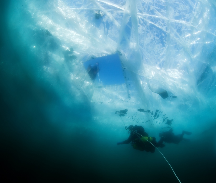 Several ice divers make their way back to the surface after practicing techniques learned during their training