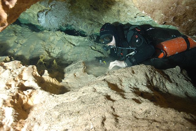 Sidemount diver exploring a cave enters a tight space