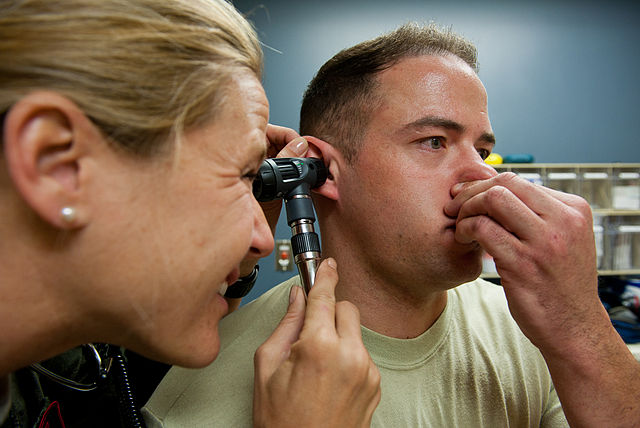 Male freediver performs the Valsalva Maneuver in his doctors office to ensure his ears clear properly after an injury
