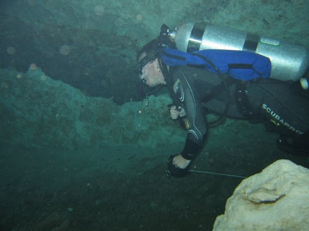 Male diver running a reel from open water into an overhead environment in a popular cave in the United States