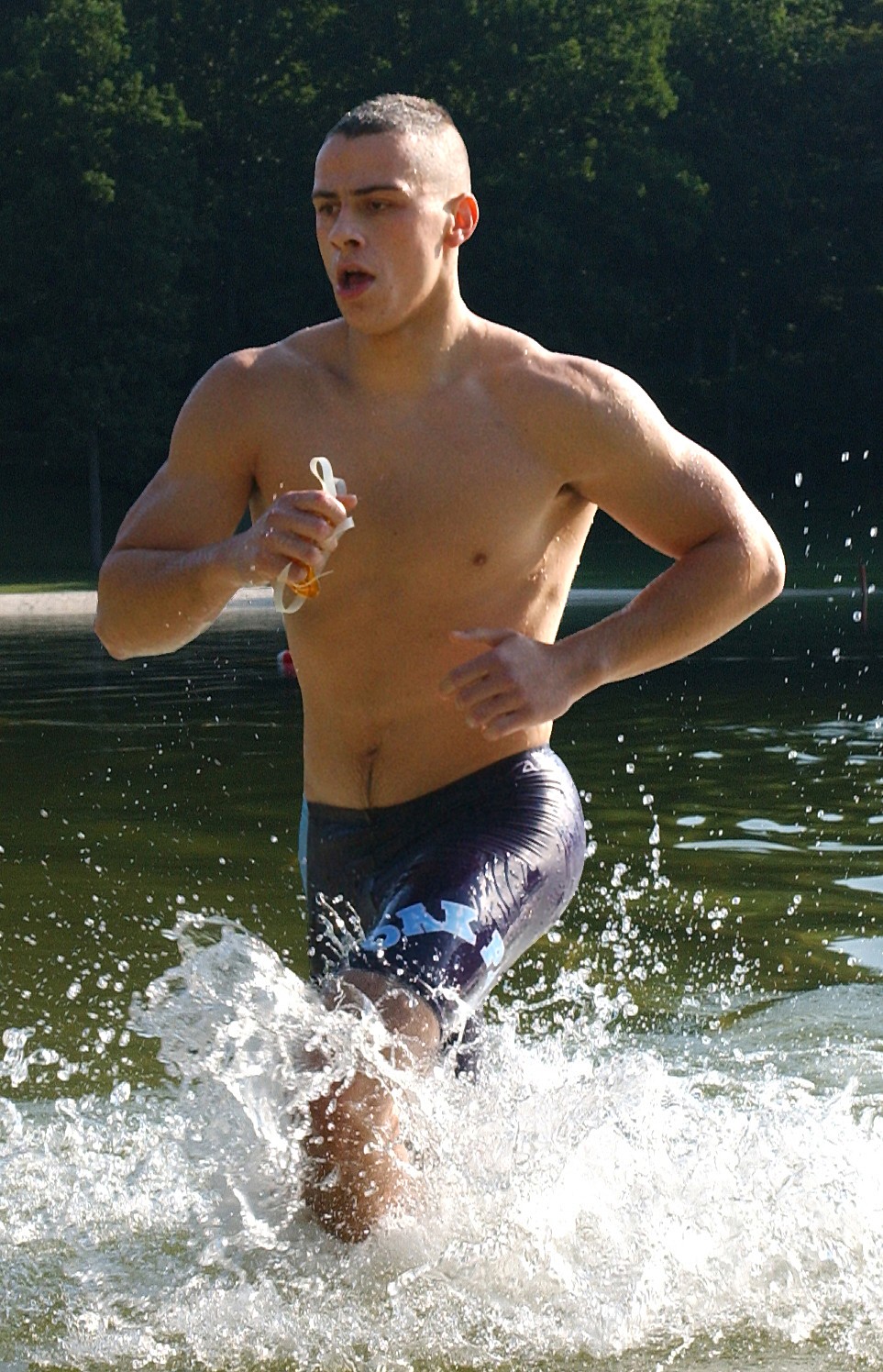 Male diver running through water in a creek as he exits the swimming portion of a triathalon