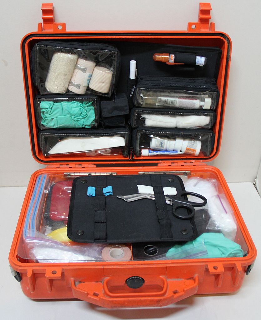 Orange waterproof first aid kit with alcohol, tape, gauze, bandages, otc pain relievers, scissors, tweezers, gloves, and more