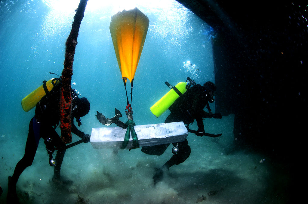 Two scuba divers from the Israel Defense Forces use lift bags to raise their underwater finds