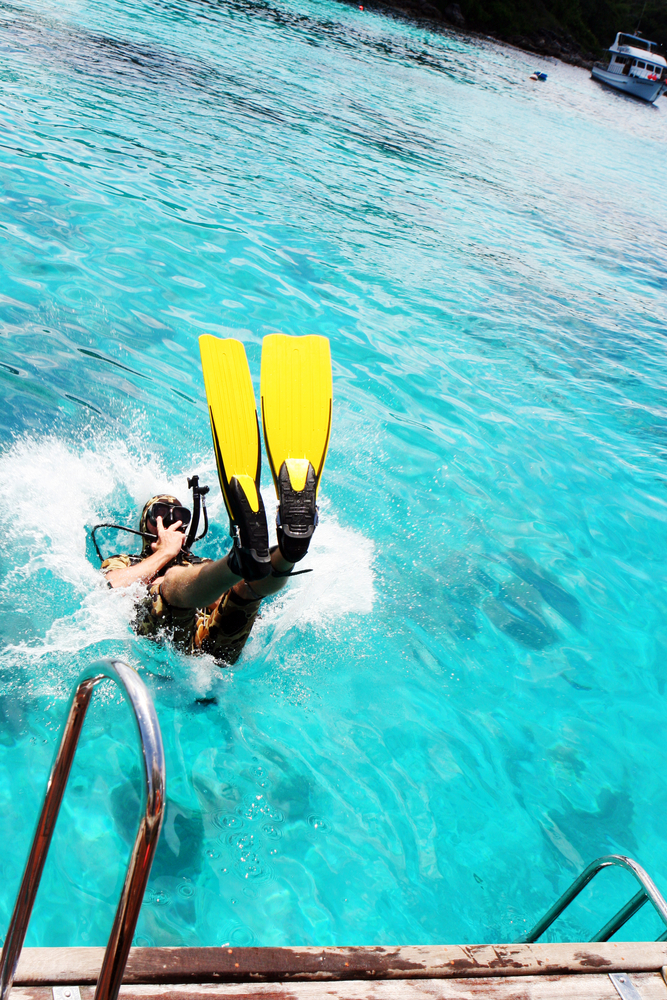 Diver practices a back roll entry from the dive boat into the clear blue waters