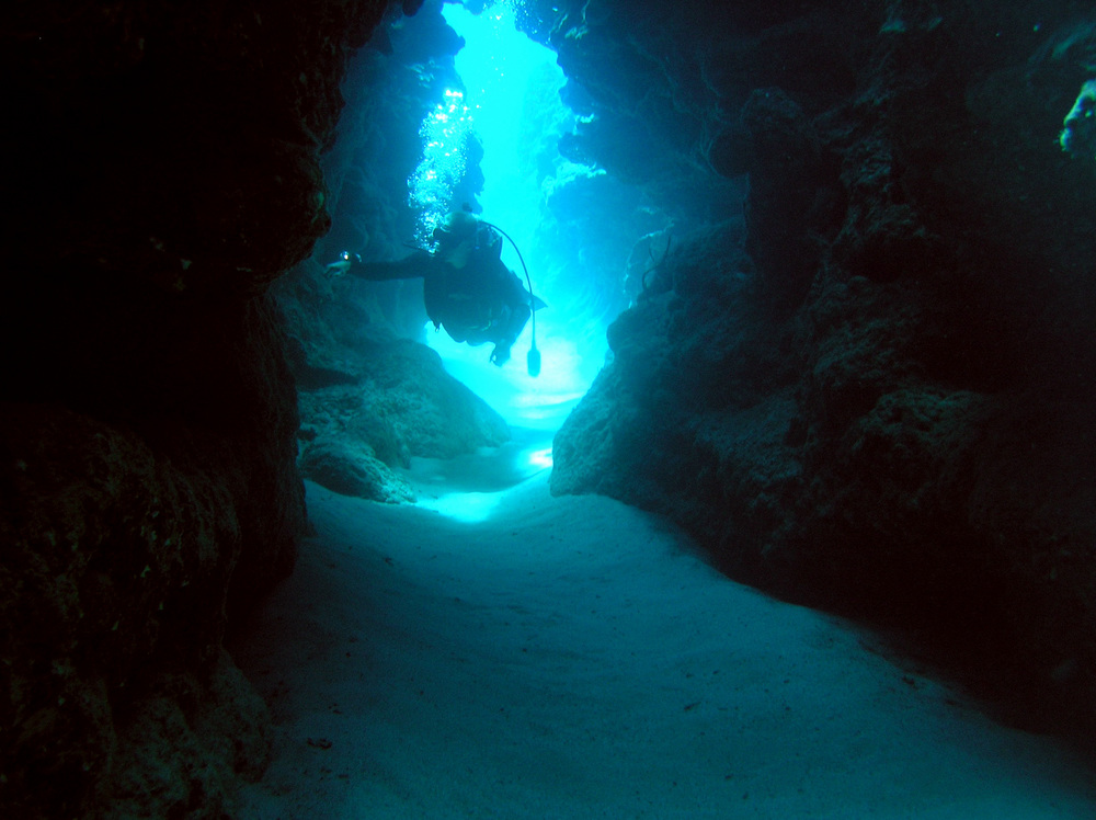 Diver enters a cave with his flashlight