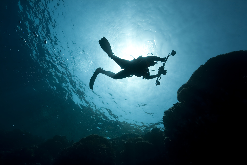 Film production safety diver makes his way to the surface with camera equipment