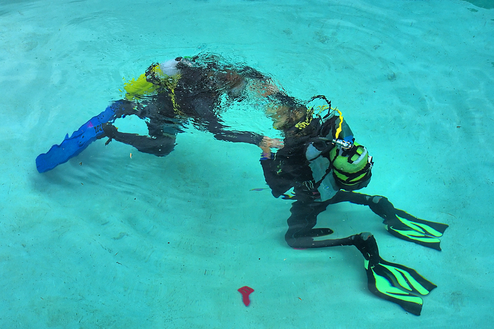 Diver practices his scuba skills in the pool by taking a refresher course while on vacation