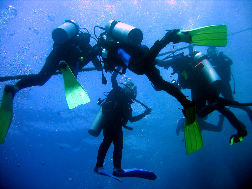 Several divers hang out together for a safety stop at an appropriate depth, reducing their risk for DCS 