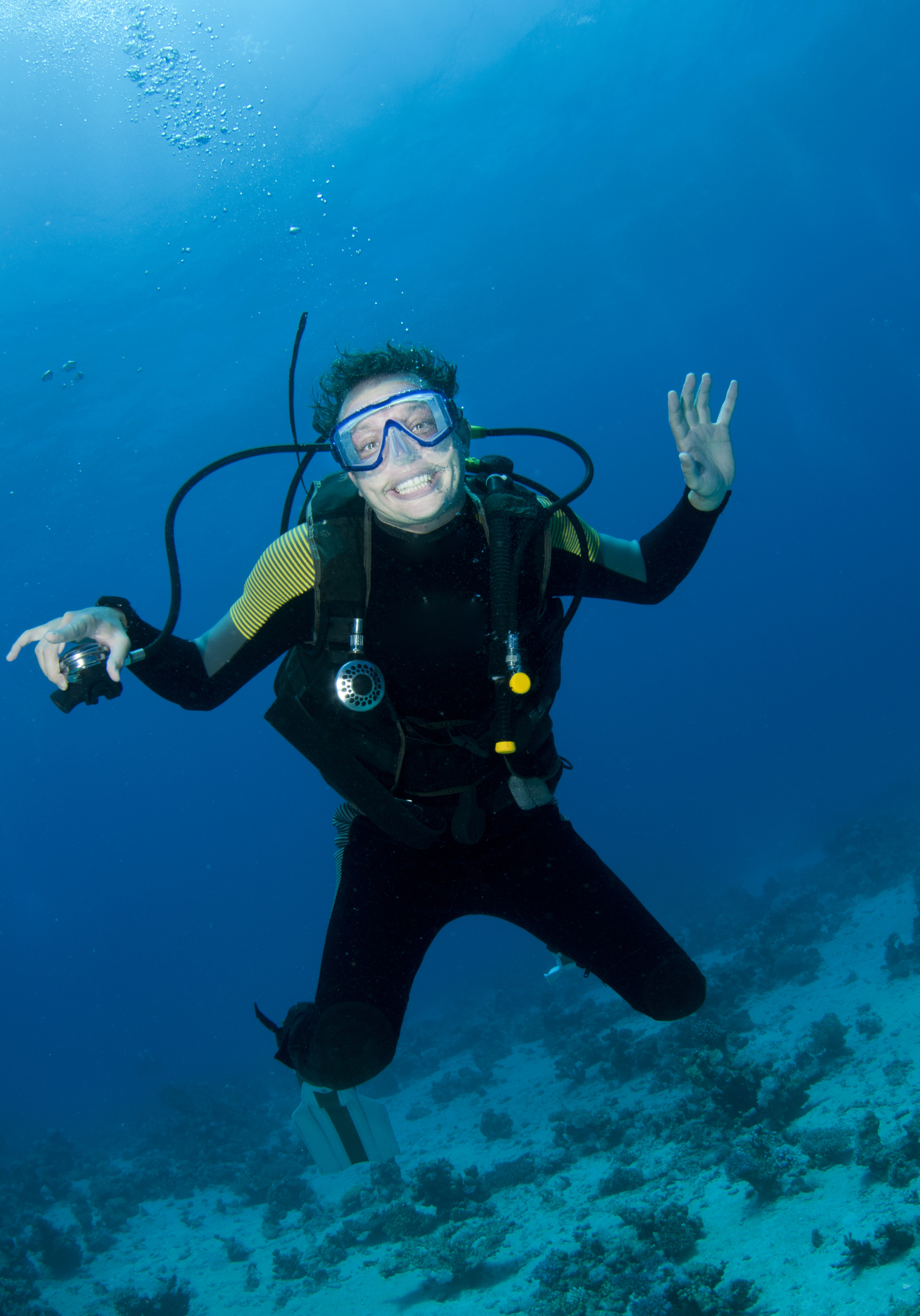 Male diver experiencing nitrogen narcosis makes a goofy smile while his regulator is removed
