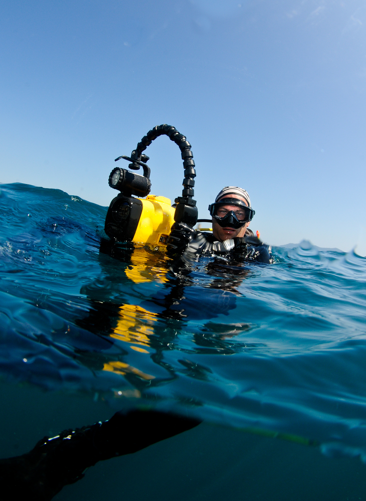 Male diver holding his underwater camera enjoys the photography expeditions offered by liveaboard operators