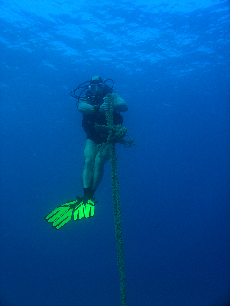 Underwater diver holding a rope sends signal to his dive buddy