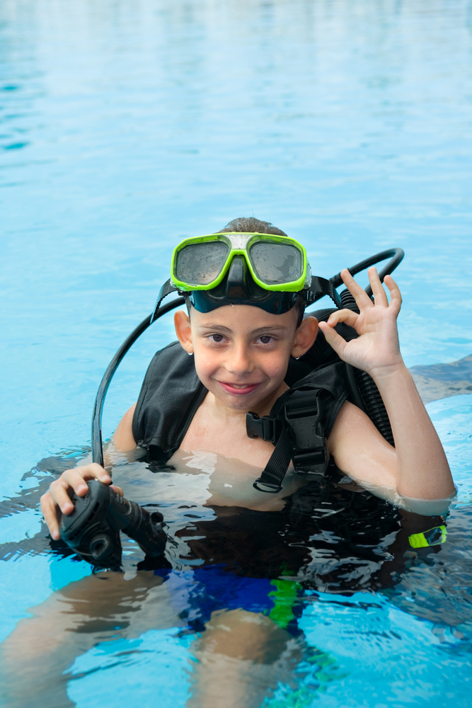Young boy learns to scuba dive in the pool while on vacation with his family