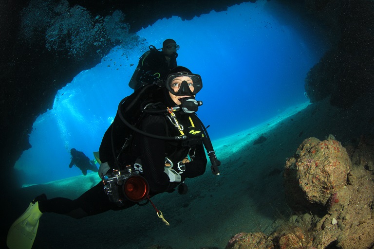 Two divers exploring swim-throughs at the Pentagon dive site on the Big Island of Hawaii