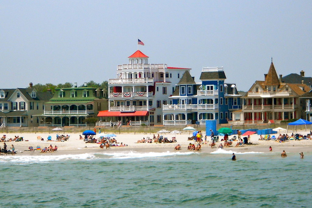 Large colorful victorian houses sit across from the white sandy beach that lines Beach Avenue in Cape May, New Jersey