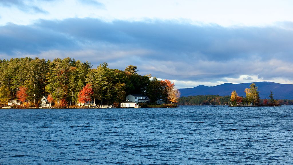 Panoramic view of Lake Winnipesaukee in Autumn surrounded by lovely homes and mountainous terrain in the backdrop