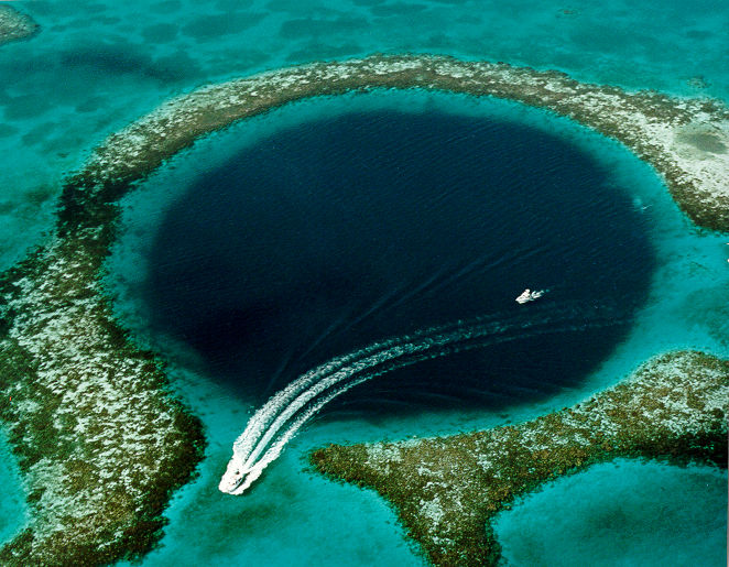 Aerial view of the Great Blue Hole in Belize with dive boats entering and leaving the area