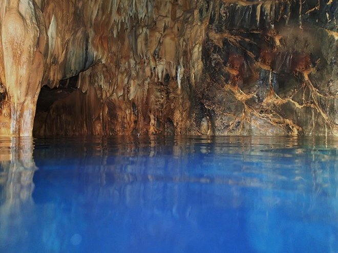 Picturesque view inside the Hedo Dome above the water with its clear blue water surrounding the stalactites and stalagmites below
