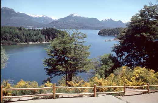 Panoramic view of Lago Nahuel Huapi in Argentina's Nahuel Huapi National Park with lush greenery surrounding the lake and whitecap mountains in the backdrop