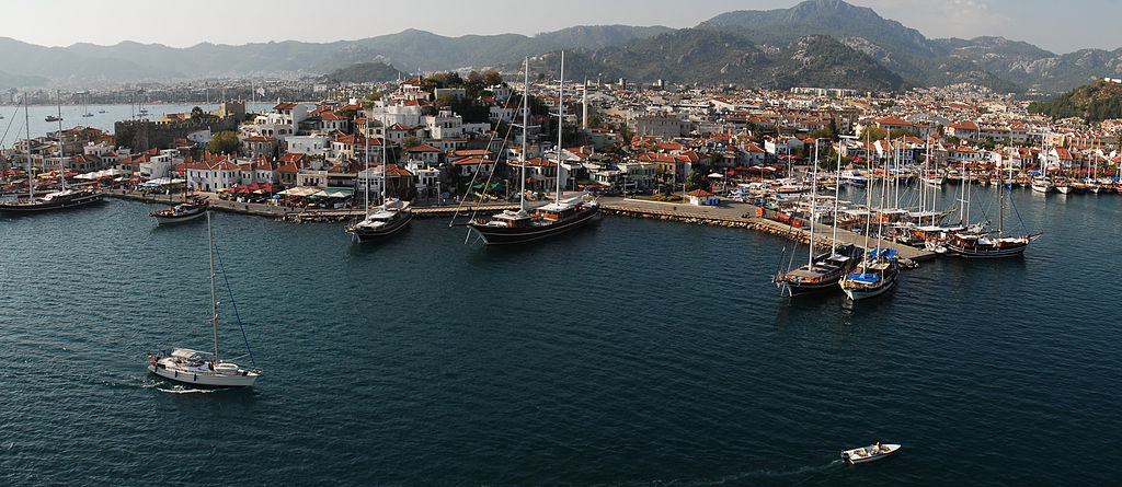 Aerial view of Turkey's Marmaris Harbor filled with boats of all kinds with the village and mountains in the backdrop