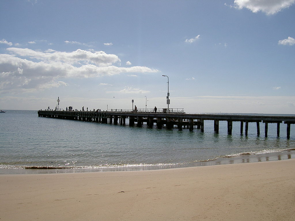 The Portsea Pier in Victoria with waves washing up against the clean sandy beach 