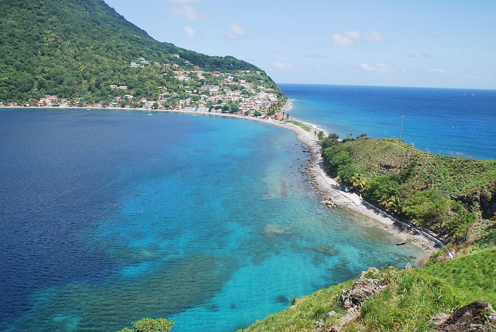 Panoramic view of Scotts Head Village and Bay surrounded by lush greenery and crystal clear blue water
