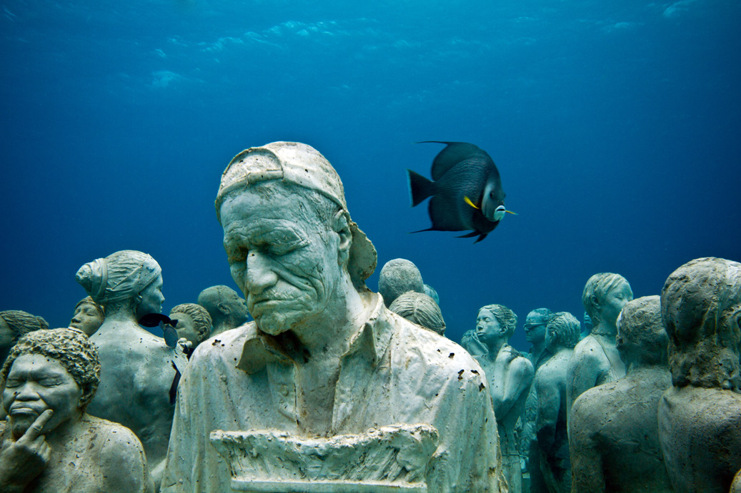 The silent evolution underwater sculpture in Cancun, Mexico was created by Jason deCaires Taylor and includes a collection of people from all walks off life which attract divers, fishes, and other marine life