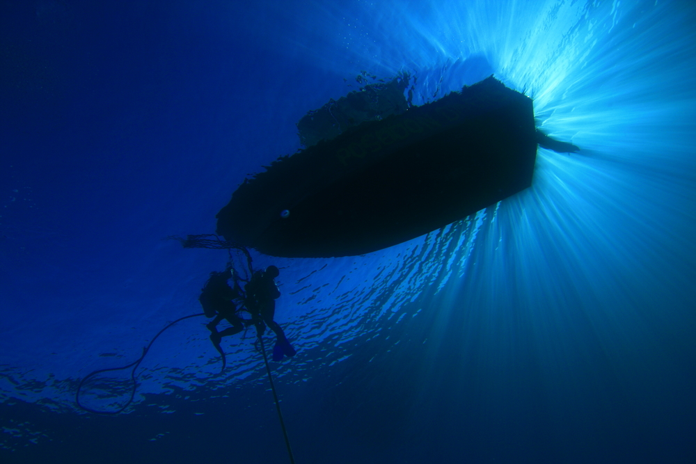 A group of divers on liveaboard excursion rest at safety stop at Maha's Rock dive site in Zubair Islands in Yemen