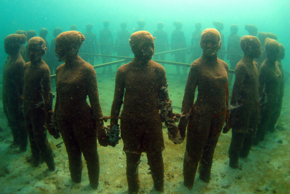 The vicissitudes, a group of children from various ethnic backgrounds, holding hands in the Caribbean waters of Grenada's Underwater Sculpture Park