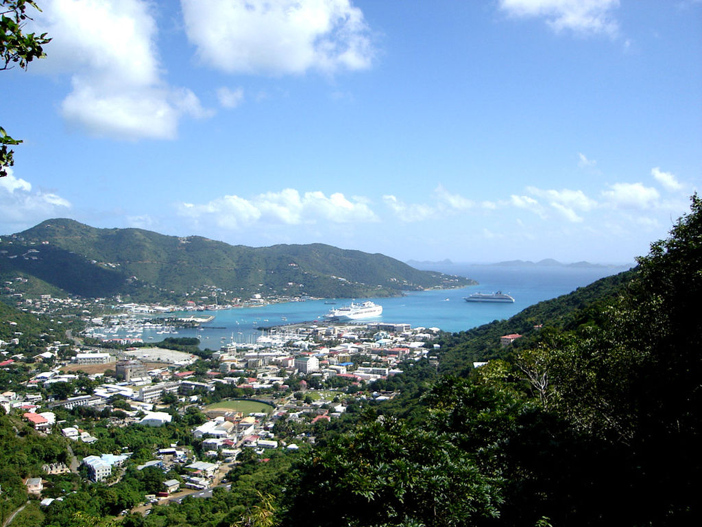 Panoramic view of Road Town on Tortola, BVI surrounded by clear blue waters and lush vegetation with several cruiselines in the distance